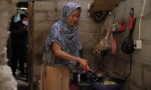 seorang ibu rumah tangga memasak menggunakan kompor listrik