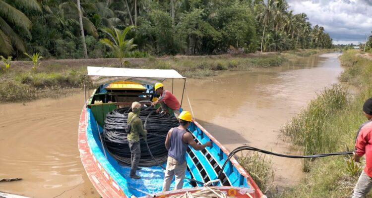 Petugas PLN saat melakukann pemasangan kabel di Desa Perajen Jaya, Kabupaten Banyuasin