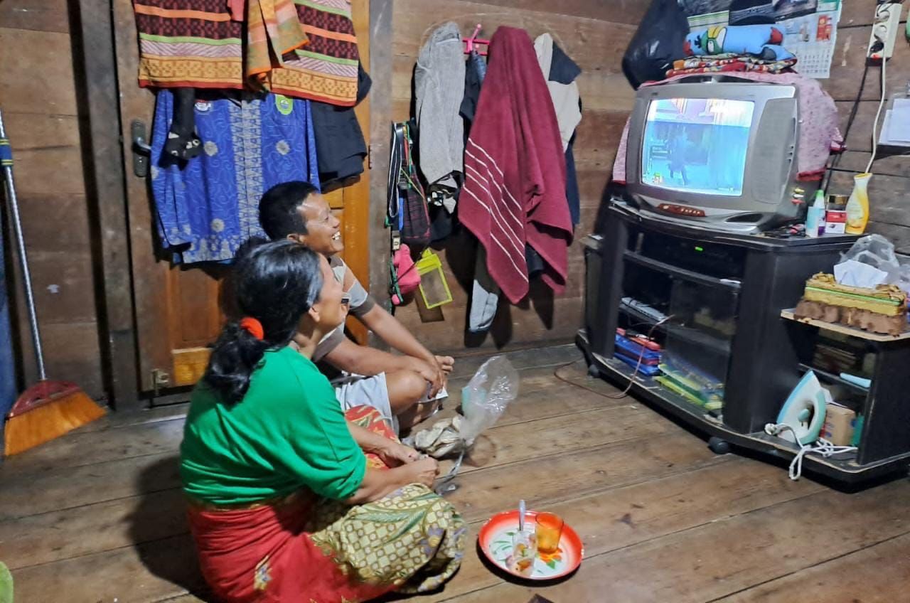 warga menonton televisi, merasakan manfaat program listrik masuk desa